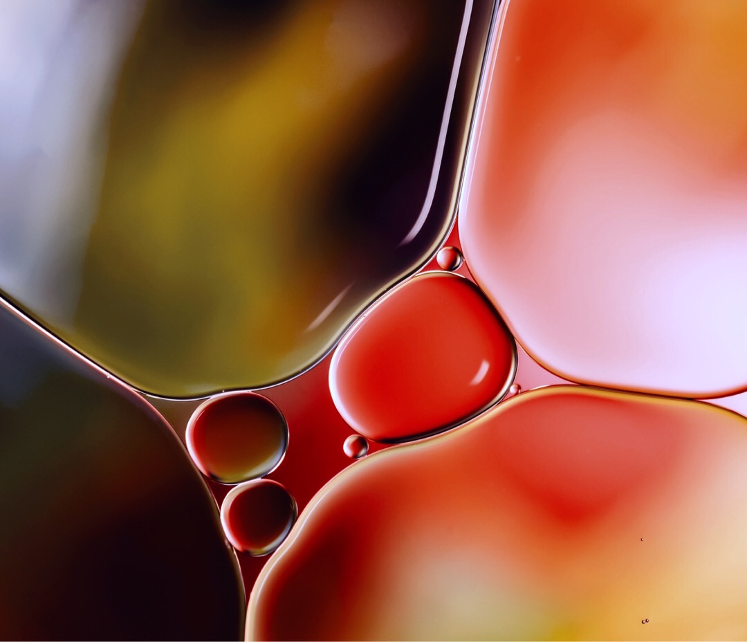 Oil on water with pink, green and red tones